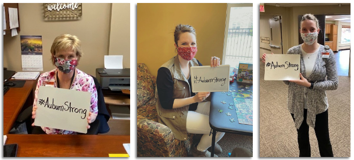 Auburn Homes & Services employees holding #AuburnStrong signs.