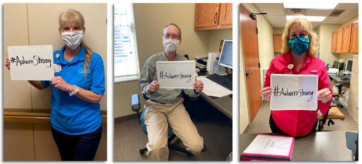 Auburn Homes & Services employees holding #AuburnStrong signs.