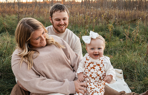 Brogan, a registered nurse, sits with her family outdoors.