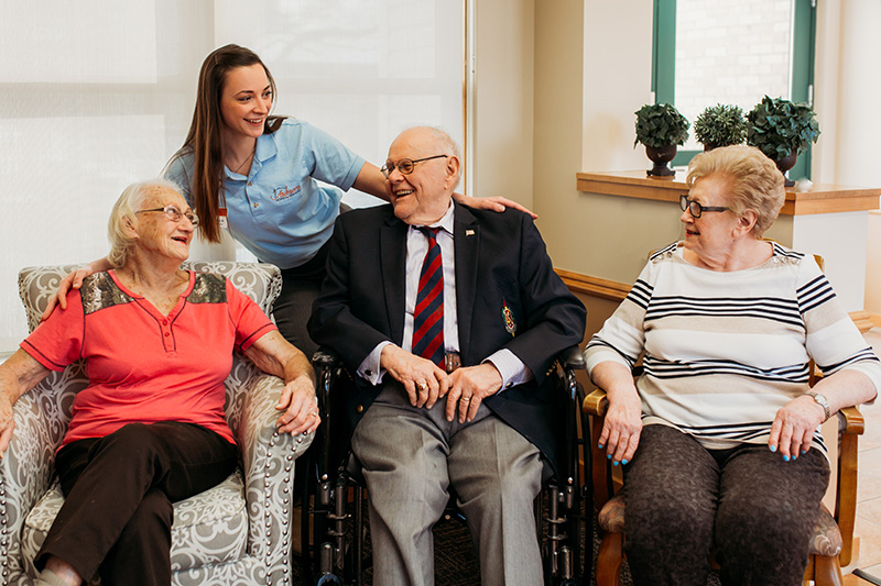 At Auburn Courts in Chaska, a Care Attendant looks on as three residents chat