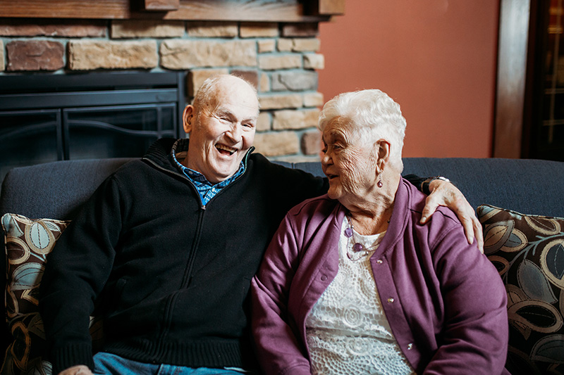 A married couple sit on a couch at Auburn Meadows in Waconia